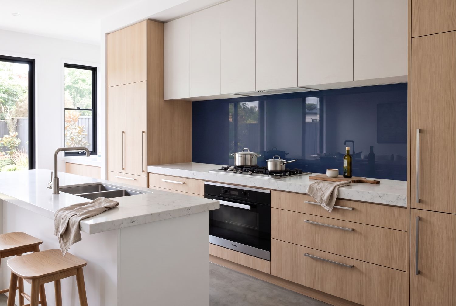 Kitchen with a navy glass splashback